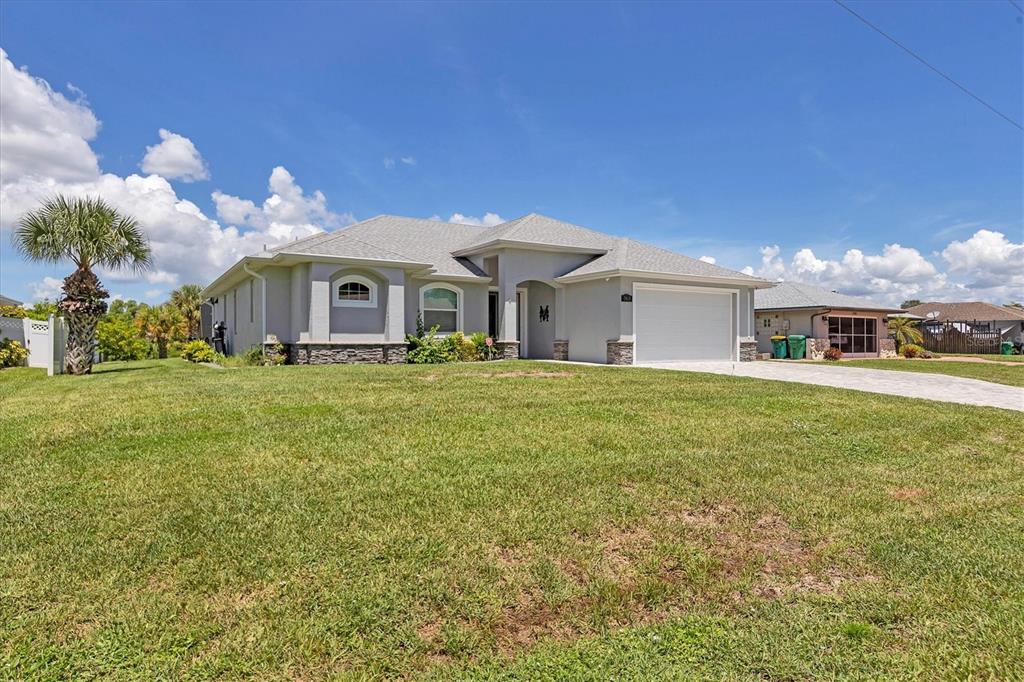 A single-story house with a gray exterior, stone accents, and a two-car garage — 7403 SNOW DRIVE, ENGLEWOOD, FL