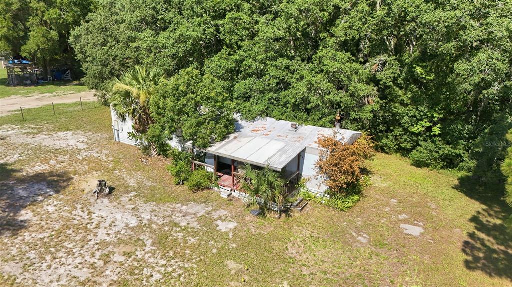 An aerial view shows a weathered mobile home with a metal roof and front porch — 37807 DEERWOODS DRIVE, EUSTIS, FL