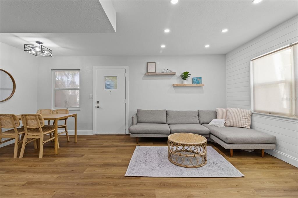 A living and dining room features light wood flooring, a gray sectional, and white walls — 9895 1ST STREET E UNIT 5, TREASURE ISLAND, FL