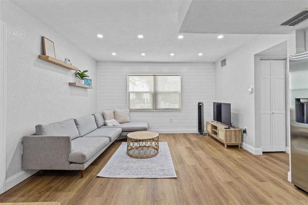 A living room features a gray sectional sofa, a round coffee table, and shiplap wall accents — 9895 1ST STREET E UNIT 5, TREASURE ISLAND, FL