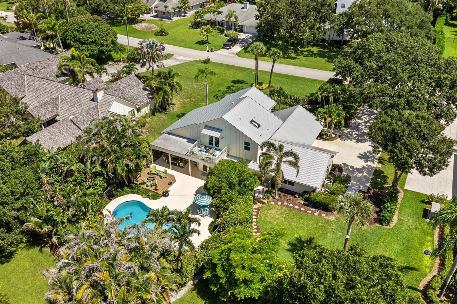 An aerial view of a house with a metal roof, swimming pool, and lush landscaping — 19646 Red Maple Lane, Jupiter FL 33458, JUPITER, FL