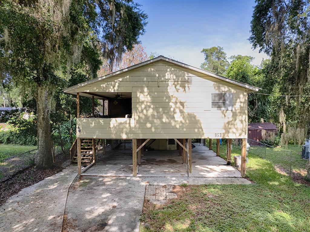 An elevated house with a concrete ground-level parking area and a wooden staircase — 853 CR 484, LAKE PANASOFFKEE, FL