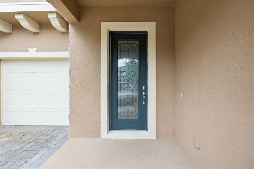 A dark blue front door with decorative glass sits next to a white garage door — 9447 PRINCE HARRY DRIVE, ORLANDO, FL