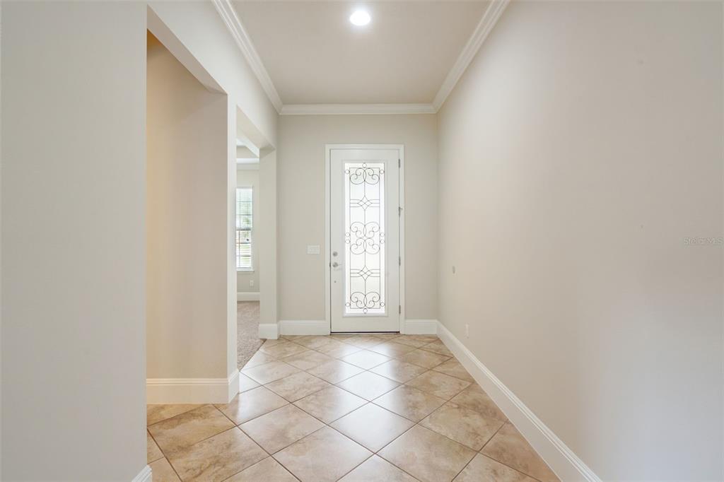 A tiled entryway features a white front door with decorative glass and crown molding — 9447 PRINCE HARRY DRIVE, ORLANDO, FL