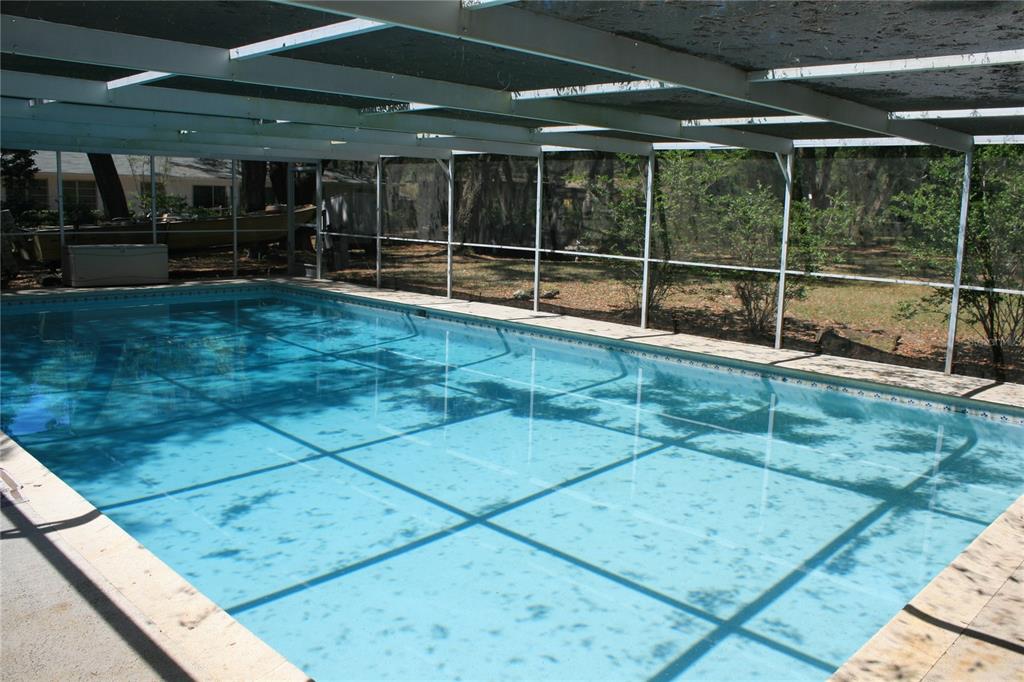 A rectangular swimming pool is enclosed by a screened-in lanai with a white metal frame — 106 SW 38TH STREET, GAINESVILLE, FL