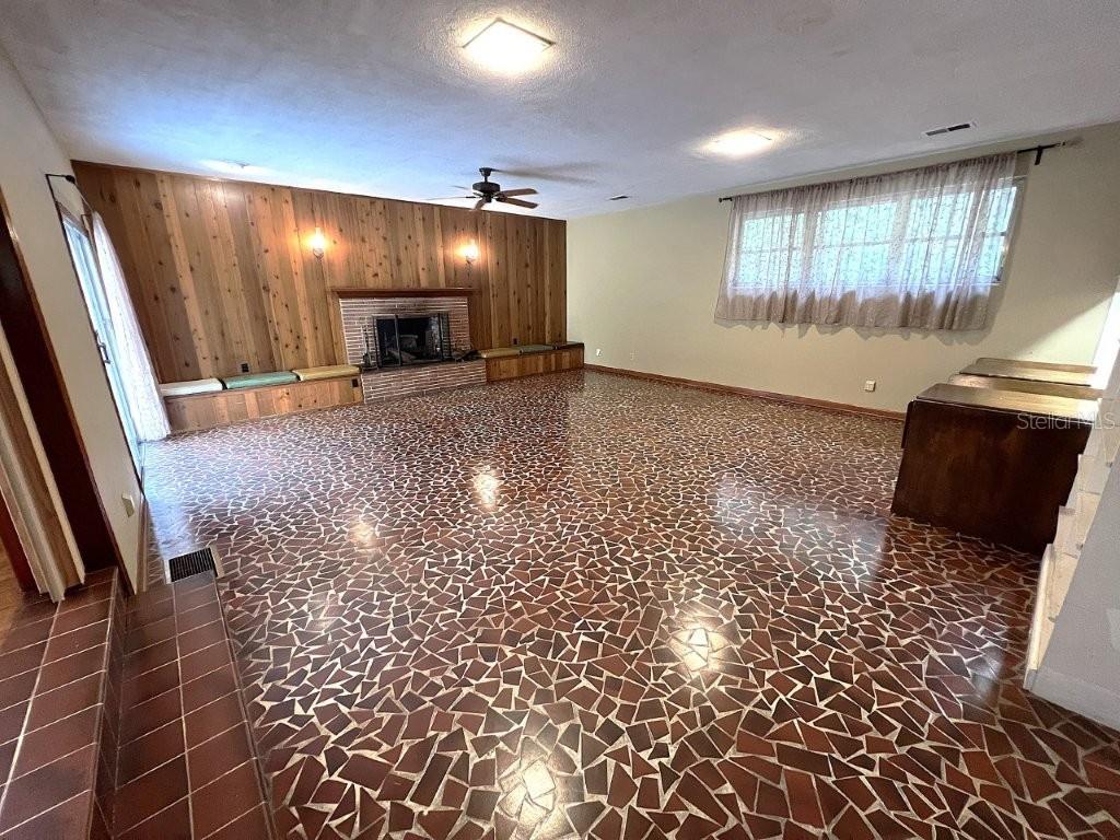 A large living room features a wood-paneled fireplace wall and a mosaic tile floor — 106 SW 38TH STREET, GAINESVILLE, FL