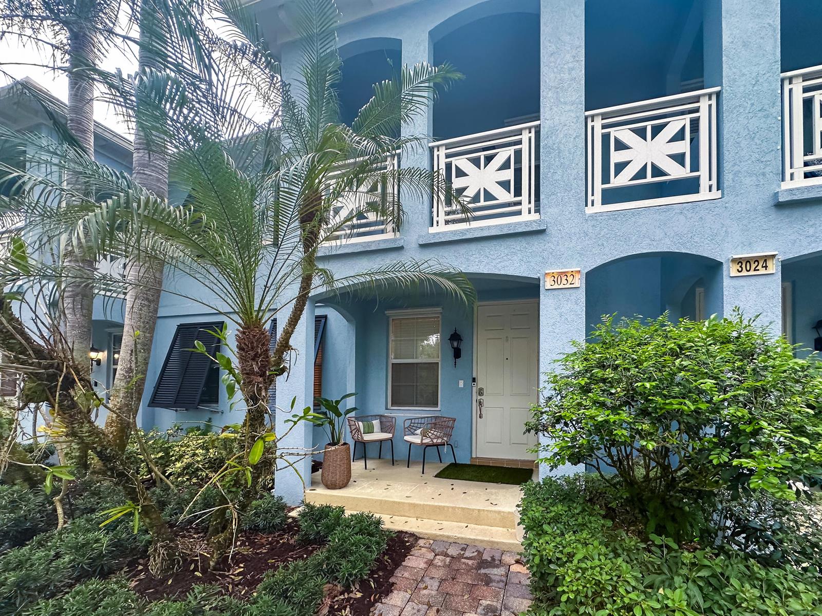 A blue two-story building features white railings, a front porch, and a brick walkway — 3032 W Community Drive, Jupiter FL 33458, JUPITER, FL