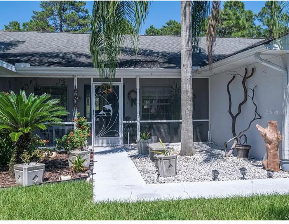 The exterior of a house features a screened front porch, a palm tree, and landscaping — 4353 W PINE RIDGE BOULEVARD, BEVERLY HILLS, FL