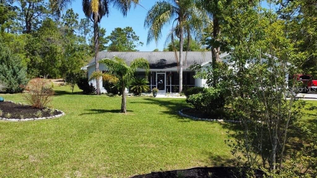 A white single-story house with a screened front porch sits on a grassy, landscaped lot — 4353 W PINE RIDGE BOULEVARD, BEVERLY HILLS, FL