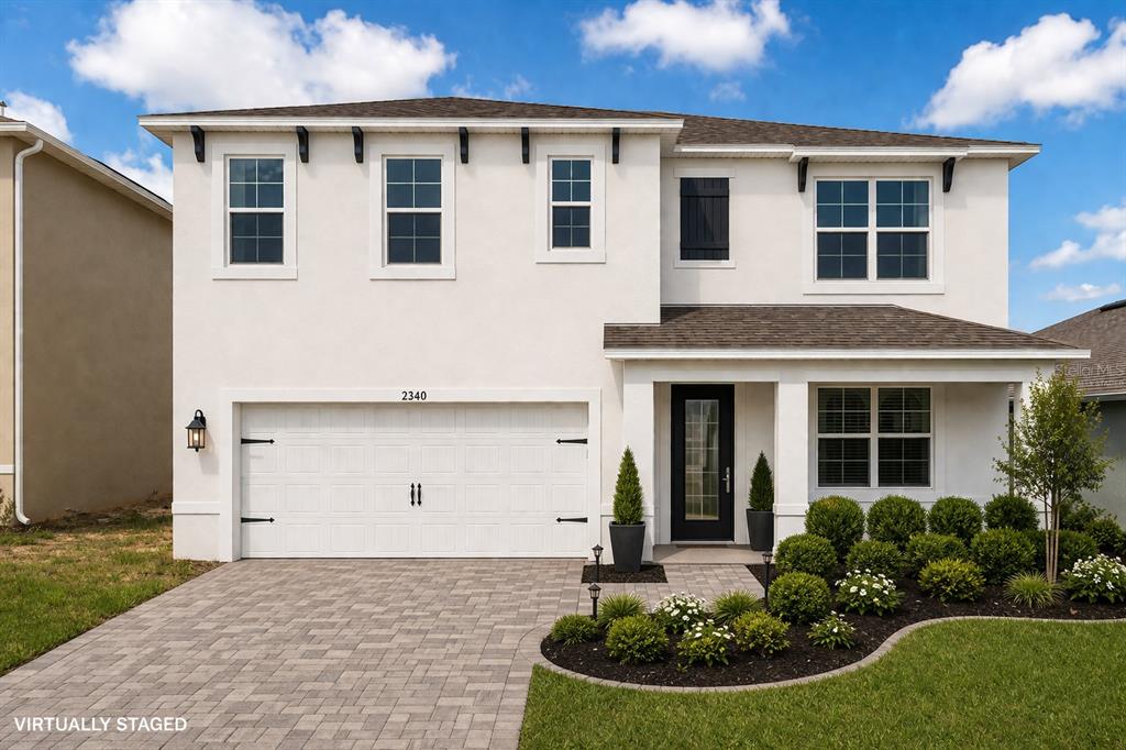 A two-story suburban house with a beige stucco exterior, a two-car garage, and a driveway — 2340 CANYON OAK DRIVE, DAVENPORT, FL