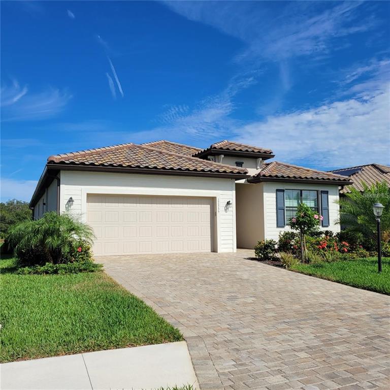 A single-story house with a beige stucco exterior, a tiled roof, and a paved driveway — 17335 BLUE RIDGE PLACE, BRADENTON, FL