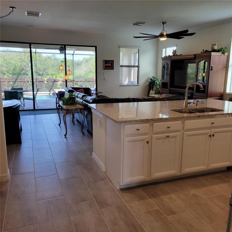 A kitchen island with granite countertops overlooks a living room and a screened-in pool area — 17335 BLUE RIDGE PLACE, BRADENTON, FL