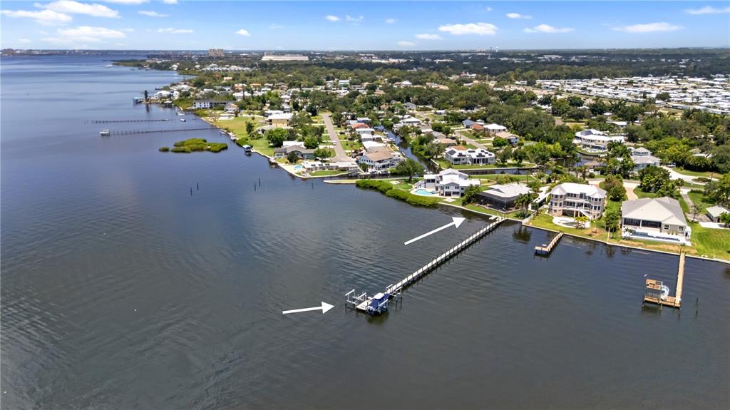 An aerial view shows a long wooden dock extending into a river from a residential property — 818 NANCY GAMBLE LANE, ELLENTON, FL