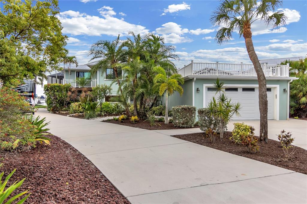 A light green house with a concrete driveway, palm trees, and a rooftop deck — 818 NANCY GAMBLE LANE, ELLENTON, FL