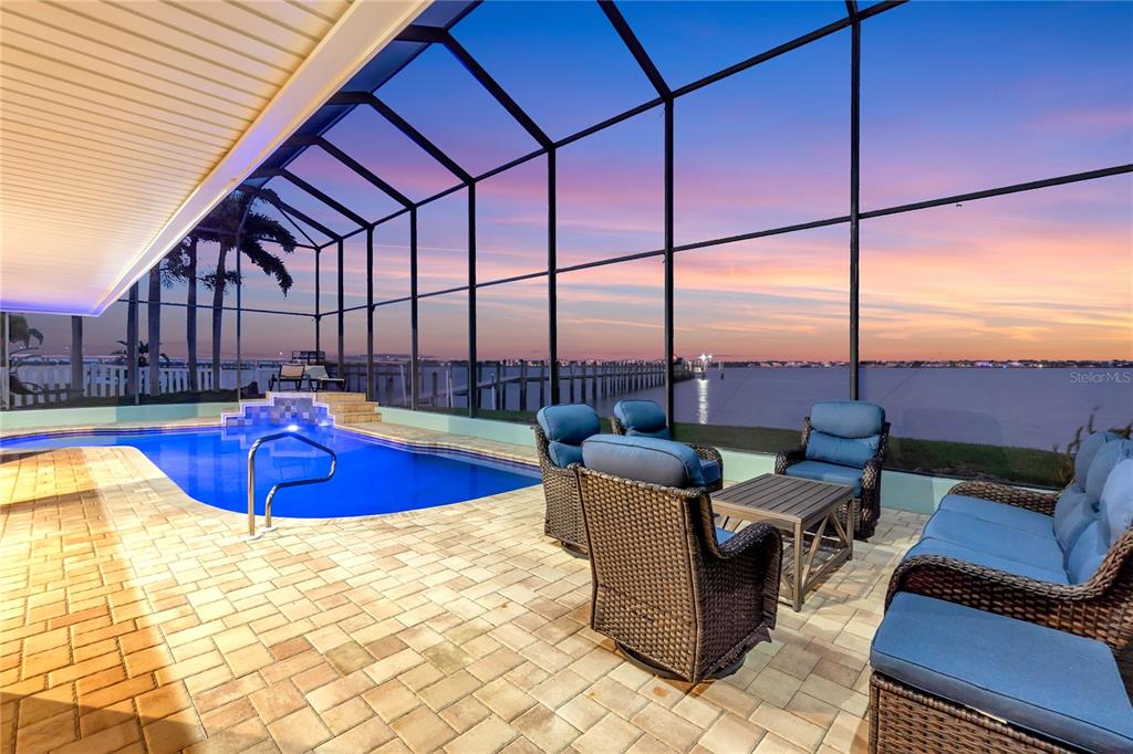 A screened-in patio features a swimming pool, outdoor furniture, and a view of the water — 818 NANCY GAMBLE LANE, ELLENTON, FL