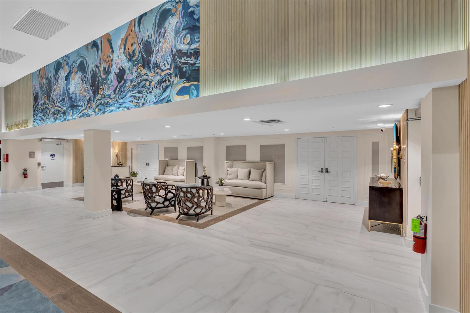 A modern lobby features a large abstract mural, white tile floors, and a seating area — 9589 Shadybrook Drive # 201, Boynton Beach FL 33437, BOYNTON BEACH, FL