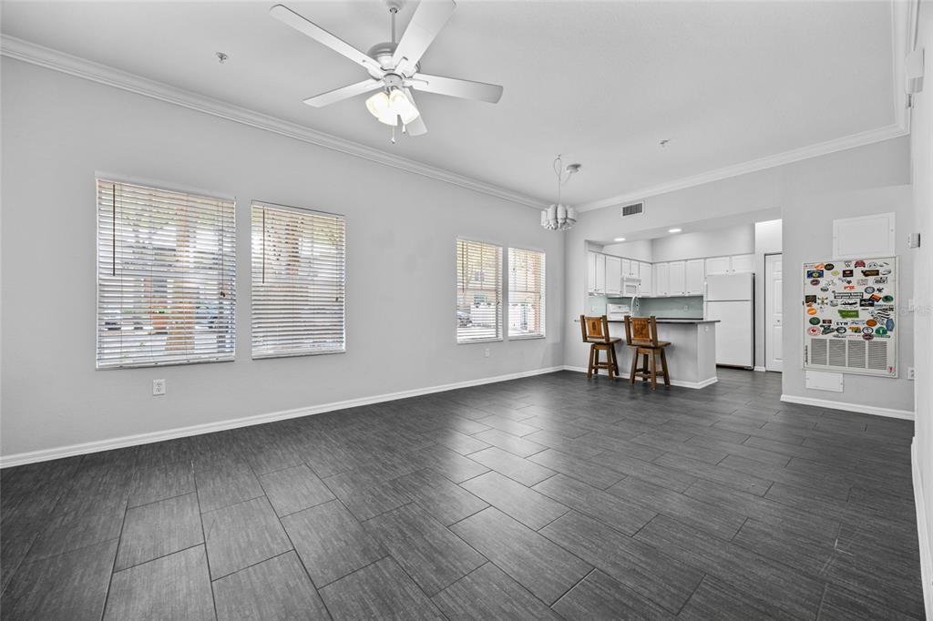 An open-concept living and dining area features gray tile flooring, white walls, and a kitchen — 5141 SW 91ST WAY UNIT I-102, GAINESVILLE, FL