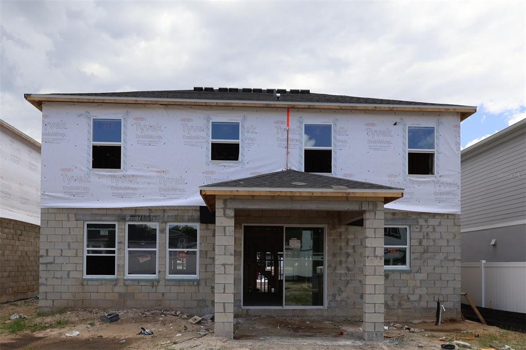 The rear exterior of a two-story house under construction with concrete blocks and Tyvek wrap — 829 RIVER STONE TRAIL, SANFORD, FL