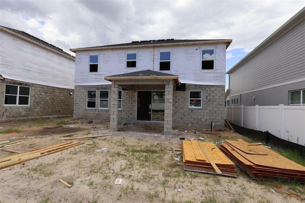 The rear exterior of a two-story house under construction features concrete block walls and Tyvek wrap — 829 RIVER STONE TRAIL, SANFORD, FL
