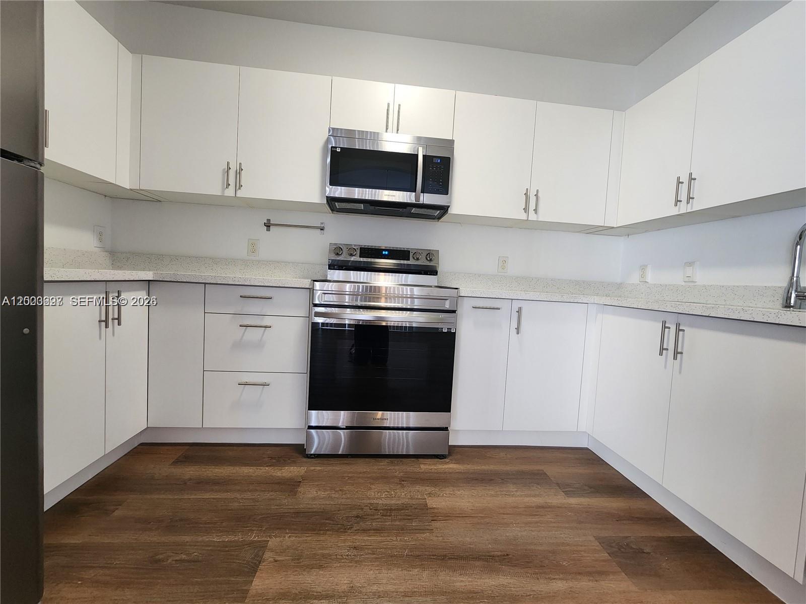 A kitchen features white cabinets, stainless steel appliances, and wood-look flooring — 15798 SW 40th St # 72, Miramar FL 33027, MIRAMAR, FL