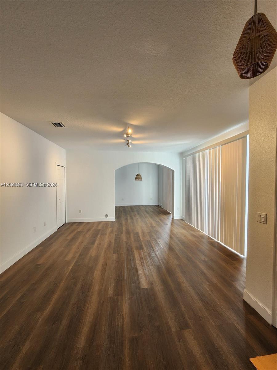 An empty living area features wood-look flooring, white walls, and a large sliding glass door — 15798 SW 40th St # 72, Miramar FL 33027, MIRAMAR, FL