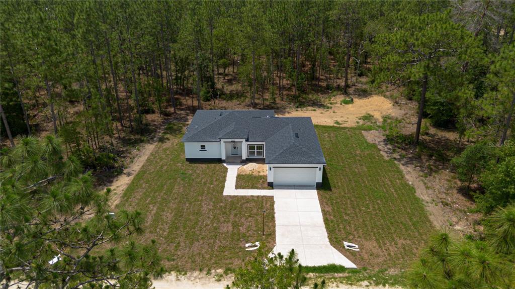 An aerial view shows a newly constructed single-story house with a driveway and surrounding forest — 12412 SW 98TH STREET, DUNNELLON, FL