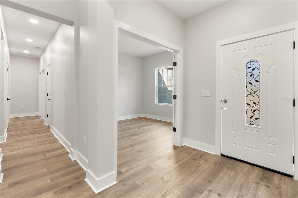 A bright entryway with light wood flooring leads to a hallway and an adjacent room — 12412 SW 98TH STREET, DUNNELLON, FL