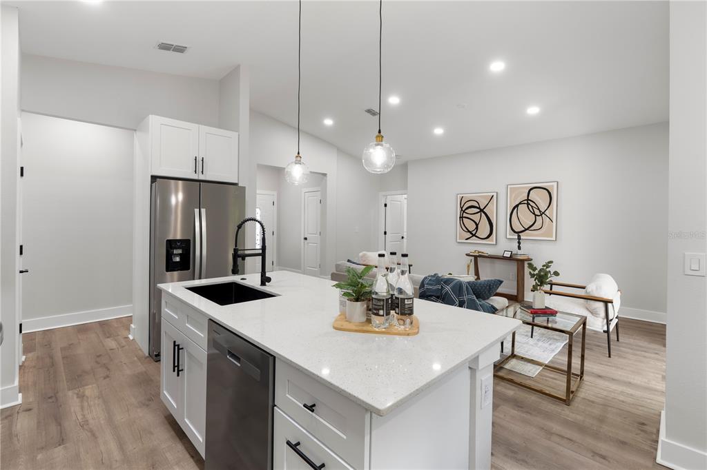 A kitchen island with a sink and dishwasher sits before a living area with artwork — 12412 SW 98TH STREET, DUNNELLON, FL