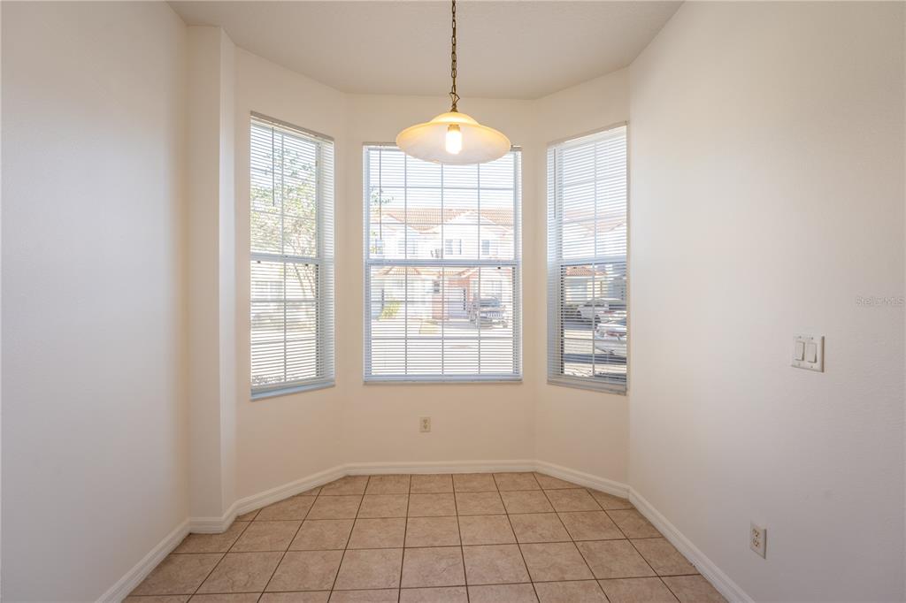 A dining nook features tile flooring, a hanging pendant light, and three large windows — 4712 HEMINGWAY HOUSE STREET, KISSIMMEE, FL