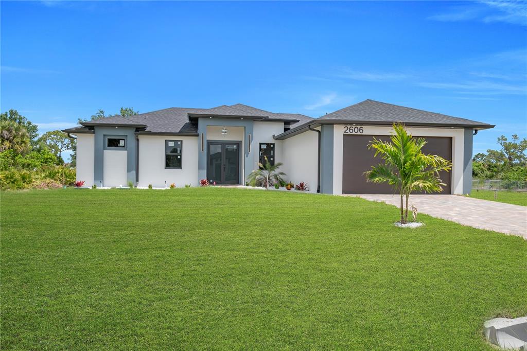 A modern, single-story house with a white stucco exterior, dark trim, and a two-car garage — 2606 40TH ST STREET, LEHIGH ACRES, FL