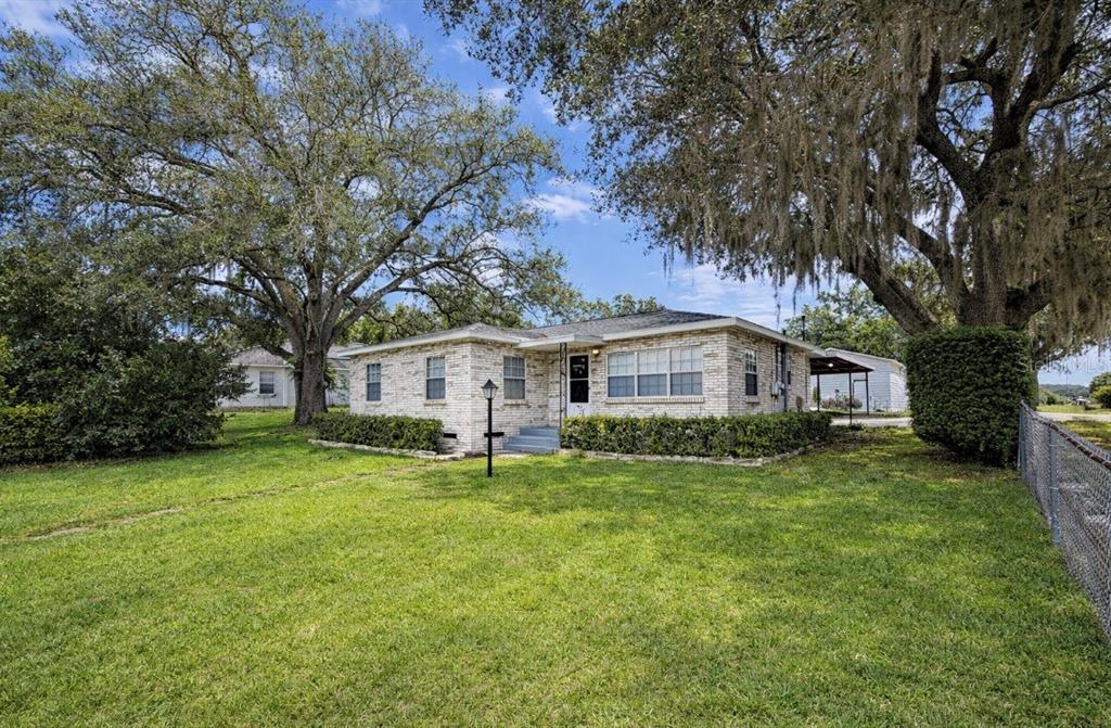 A single-story brick house with a large front lawn and mature oak trees — 118 E PINE STREET, DAVENPORT, FL