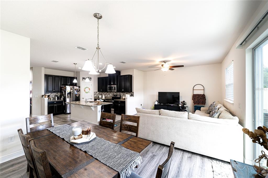 An open-concept living area features a dining table, kitchen with dark cabinets, and a sofa — 2749 PLEASANT CYPRESS CIRCLE, KISSIMMEE, FL