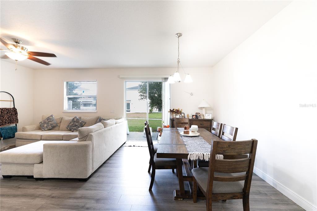 An open-concept living and dining room with light wood-look flooring and a sliding glass door — 2749 PLEASANT CYPRESS CIRCLE, KISSIMMEE, FL