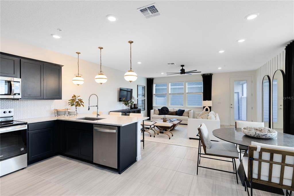 A kitchen with dark cabinets and a white island opens into a living room area — 10106 HADLEY STREET, ORLANDO, FL