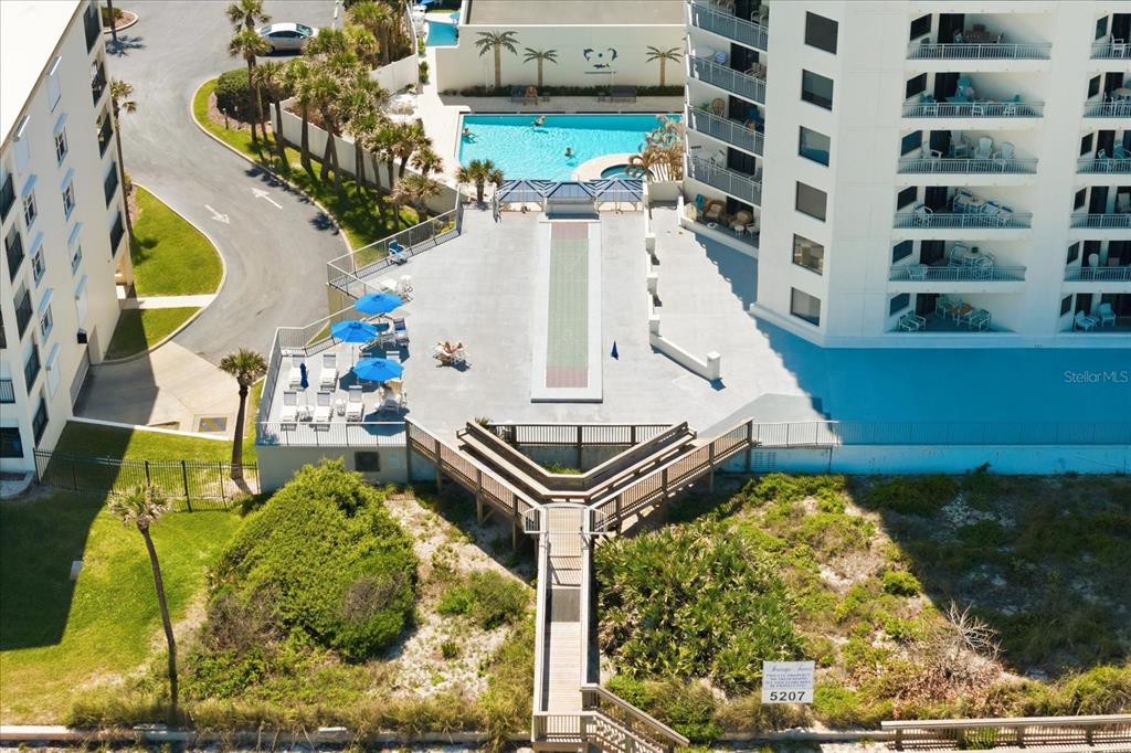 An aerial view shows a resort pool deck with a shuffleboard court and beach boardwalk — 5207 S ATLANTIC AVENUE UNIT 1025, NEW SMYRNA BEACH, FL