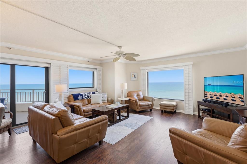 A living room with leather furniture, wood floors, and large windows overlooking the ocean — 5207 S ATLANTIC AVENUE UNIT 1025, NEW SMYRNA BEACH, FL