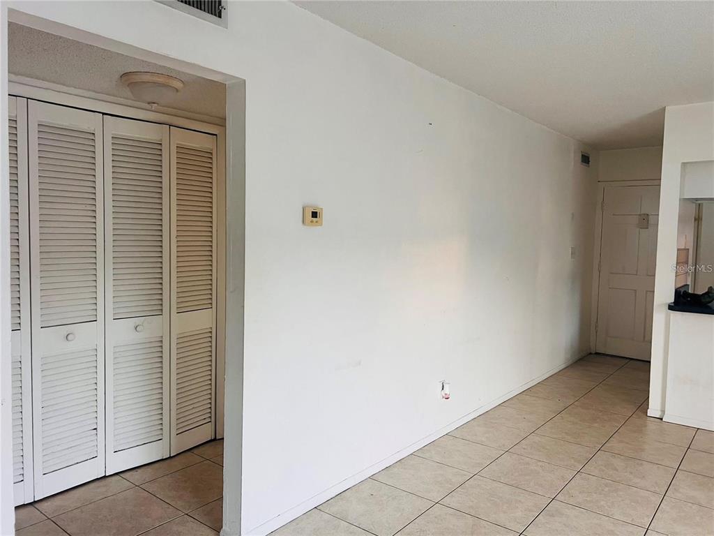 An interior view shows a tiled room with white walls, louvered closet doors, and a doorway — 1000 S SEMORAN BOULEVARD UNIT 715, WINTER PARK, FL