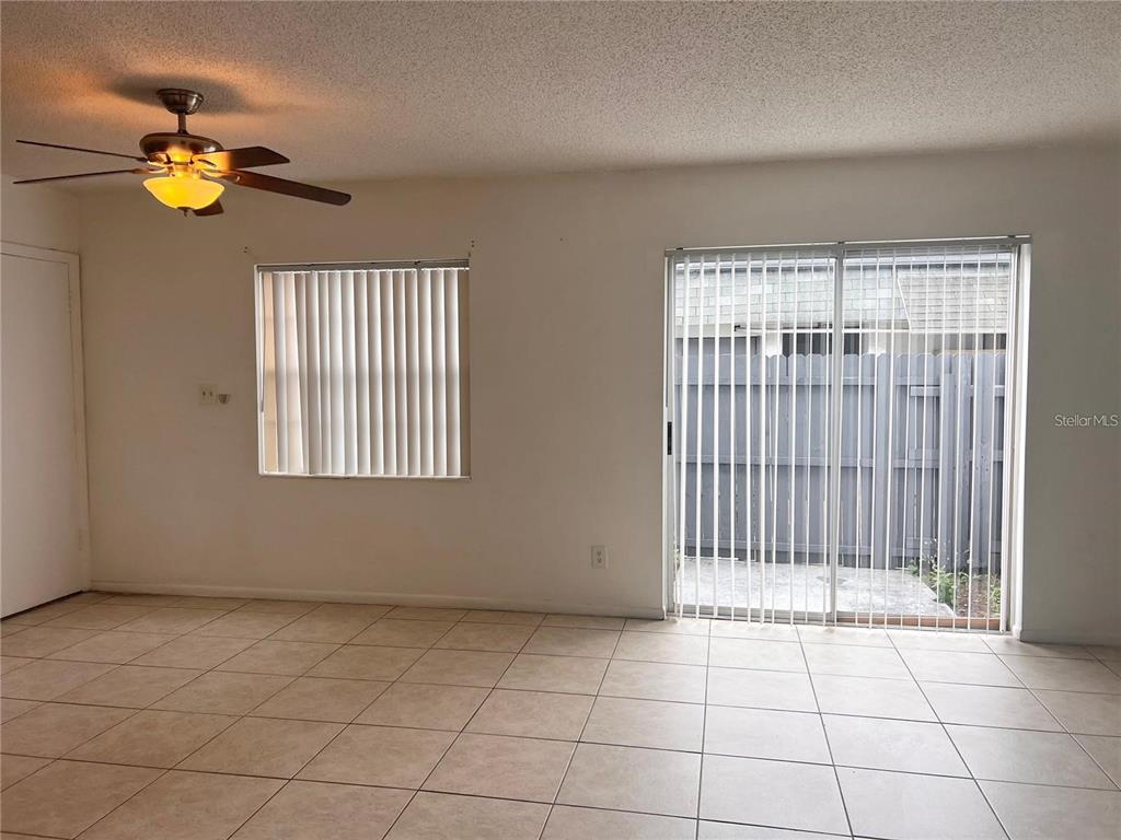 An empty room with beige tile flooring, a ceiling fan, a window, and sliding doors — 1000 S SEMORAN BOULEVARD UNIT 715, WINTER PARK, FL