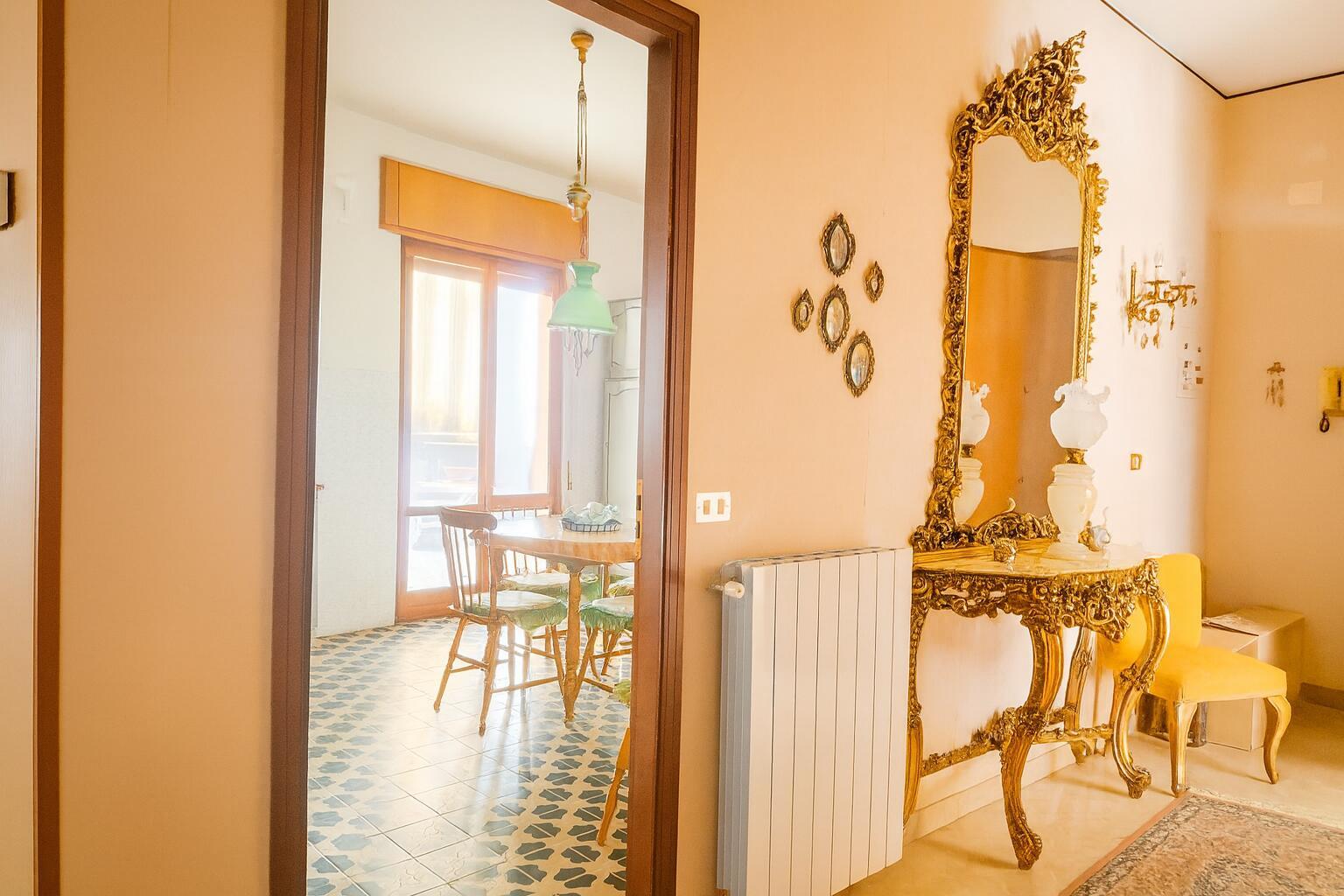 A view through a doorway into a dining room with a gold-framed mirror and console — 5 Via Italia N 5, FL