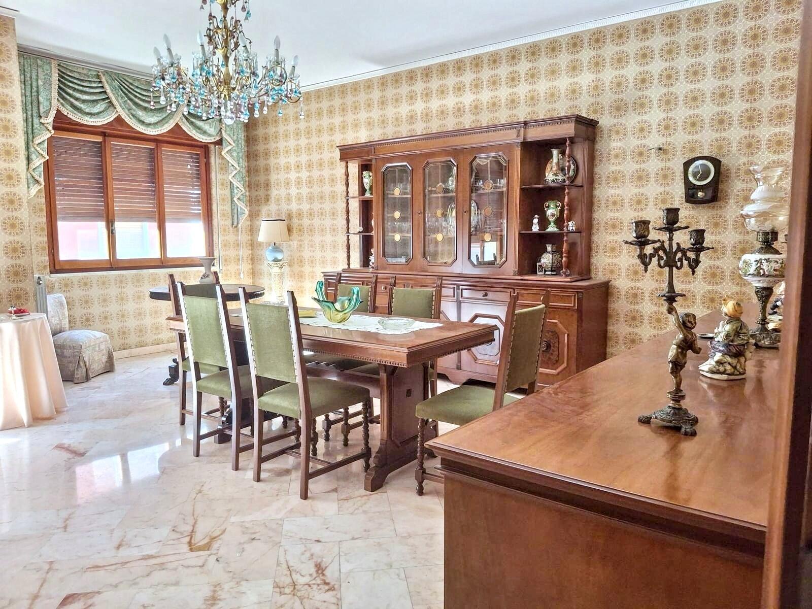 A dining room features a wooden hutch, a table with green chairs, and patterned wallpaper — 5 Via Italia N 5, FL