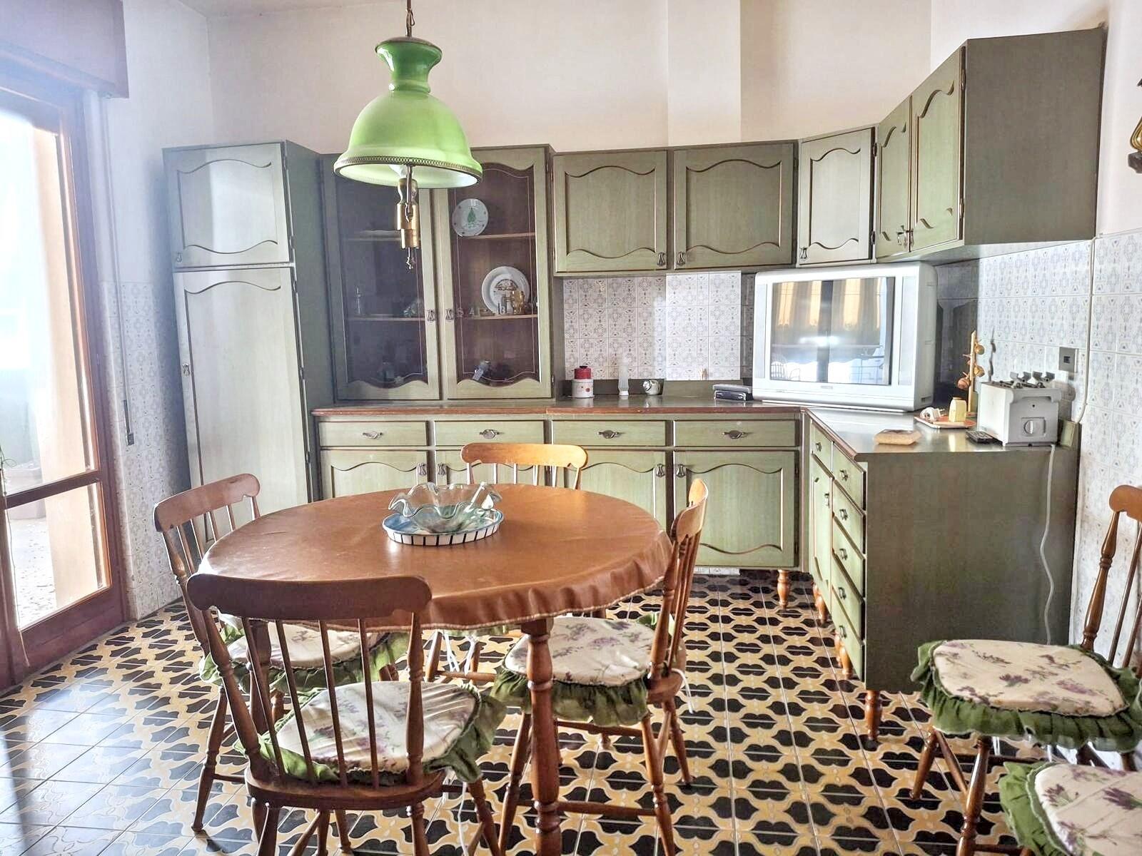 A kitchen with green cabinets, a round wooden table, and patterned tile flooring — 5 Via Italia N 5, FL