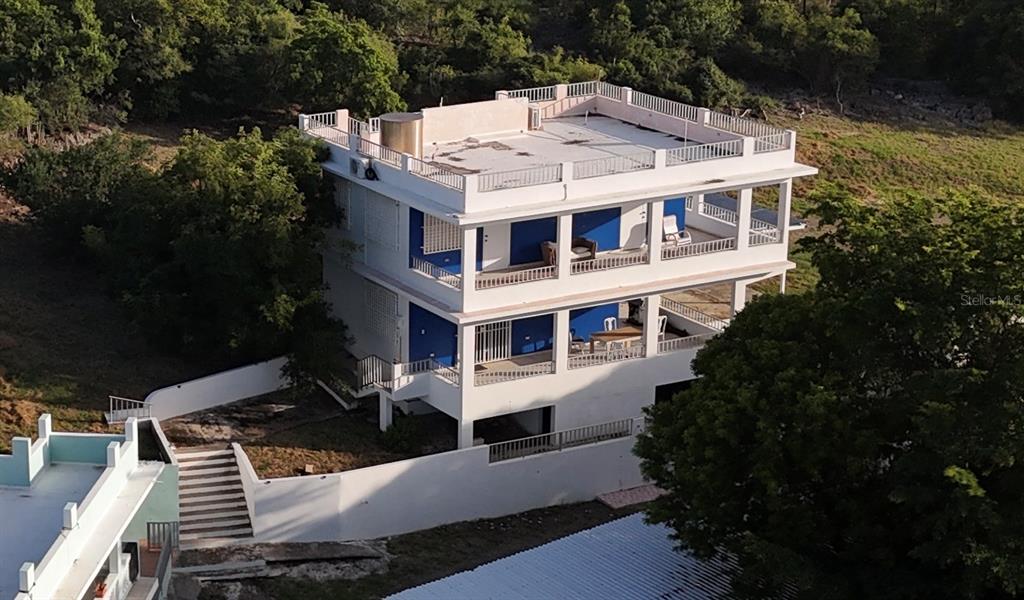 An aerial view of a three-story white house with blue accents and a rooftop terrace — 24 CALLE CORAL PLAYA SANTA, GUANICA, PR