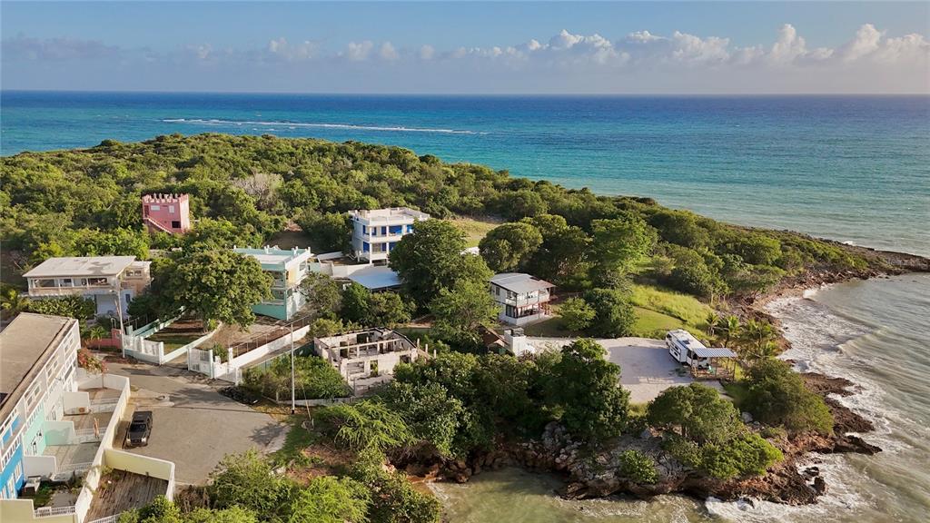 An aerial view shows several houses and a camper parked on a rocky coastal cliff — 24 CALLE CORAL PLAYA SANTA, GUANICA, PR