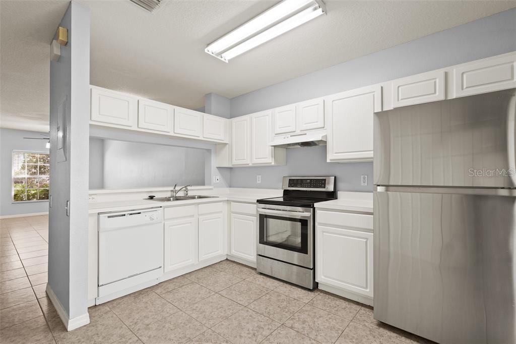 A kitchen with white cabinets, stainless steel appliances, and light-colored tile flooring — 2369 LAKE WOODBERRY CIRCLE, BRANDON, FL