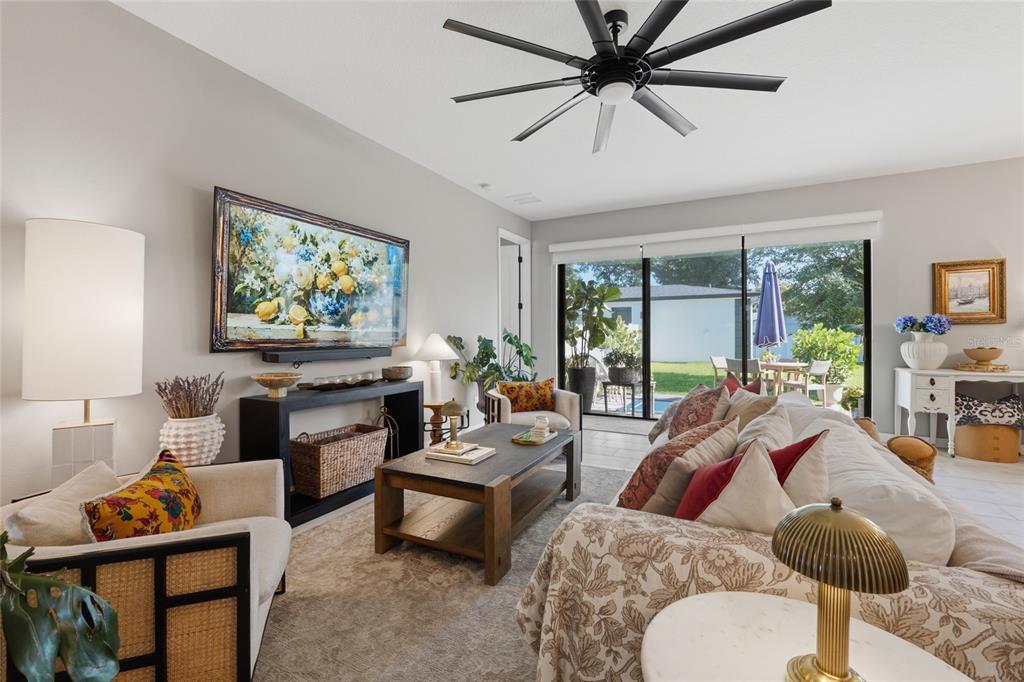 A living room features a large ceiling fan, a television, and sliding glass doors to a patio — 2015 E KALEY AVENUE, ORLANDO, FL