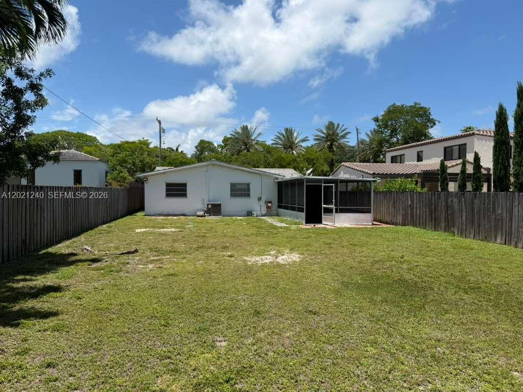 The backyard features a white house with a screened-in porch and a wooden fence — 5127 Alton Rd, Miami Beach FL 33140, MIAMI BEACH, FL