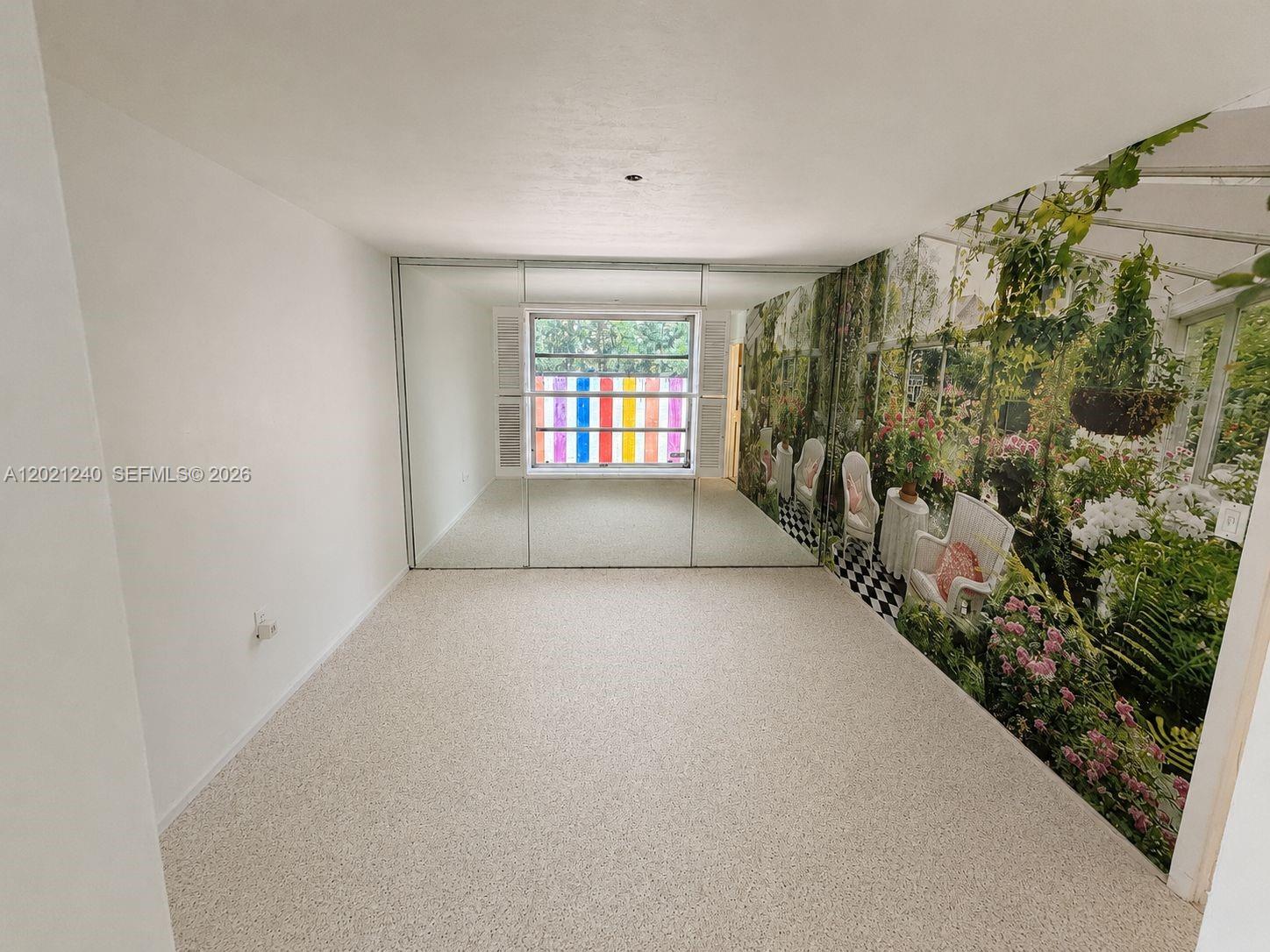 A room features beige carpeting, a mirrored closet wall, and a large garden-themed wall mural — 5127 Alton Rd, Miami Beach FL 33140, MIAMI BEACH, FL