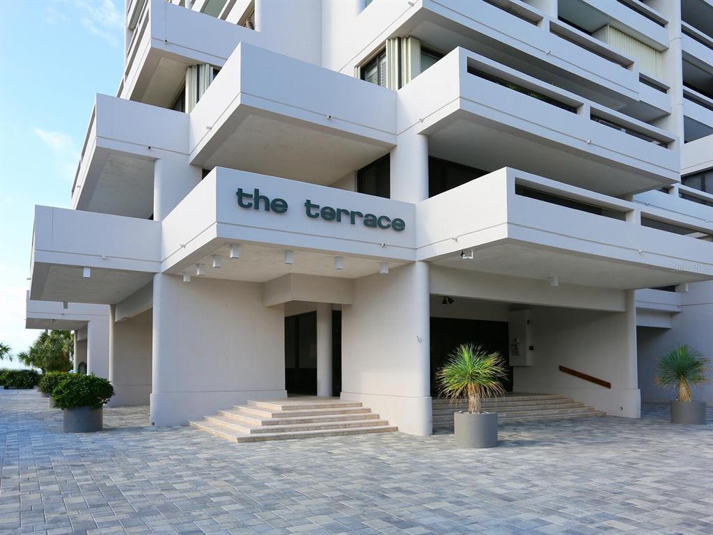 The exterior entrance of a white multi-story building features a sign reading the terrace — 5400 OCEAN BOULEVARD UNIT 5-3, SARASOTA, FL