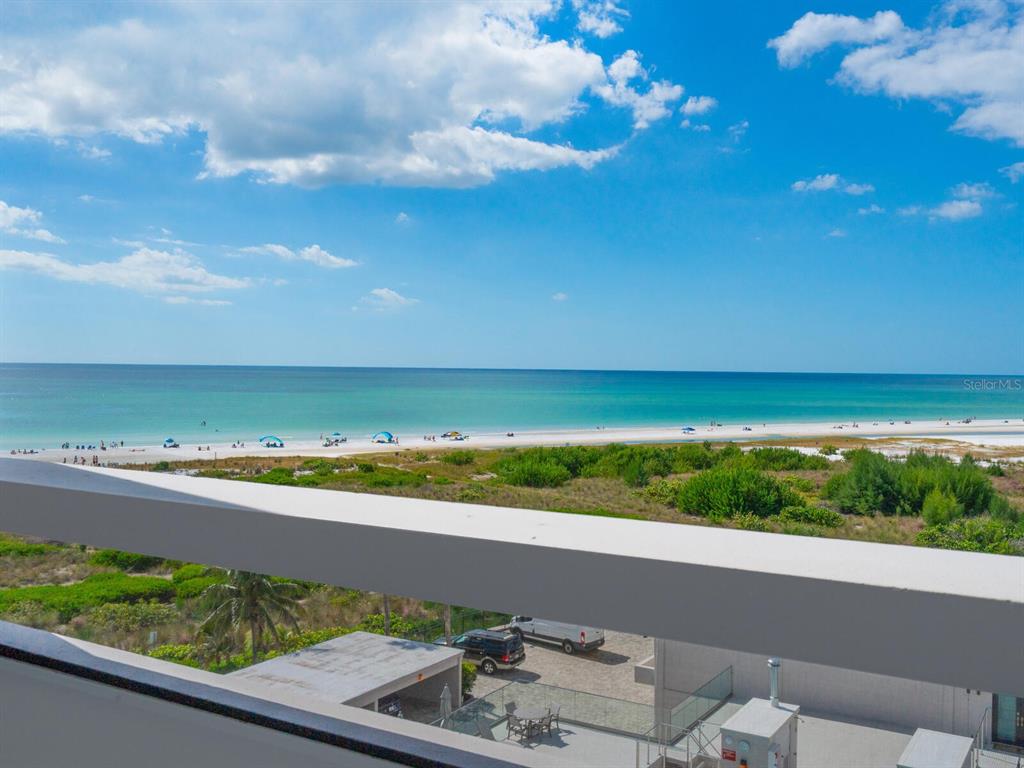 A high-angle view shows a beach with turquoise water, sand, and coastal vegetation — 5400 OCEAN BOULEVARD UNIT 5-3, SARASOTA, FL