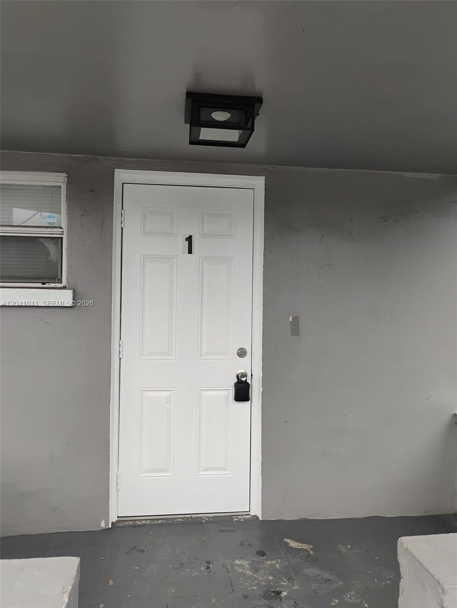 A white front door labeled with the number one is set in a gray wall — 2325 Madison St # 1, Hollywood FL 33020, HOLLYWOOD, FL